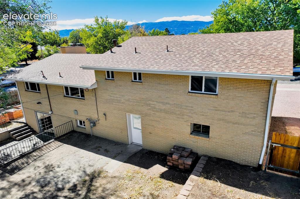 Image 19 of 50: Multi-level brick exterior with composition shingle roofing, concrete patio