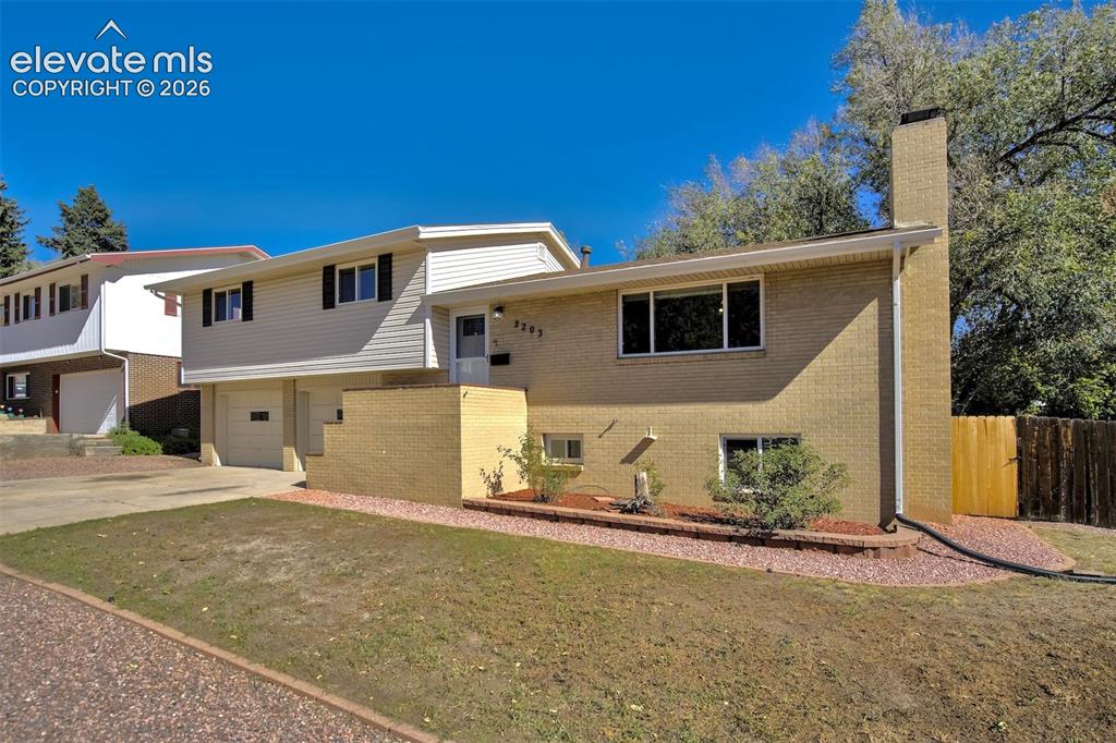 Image 2 of 50: Split-level exterior featuring light brick masonry, horizontal siding, an i