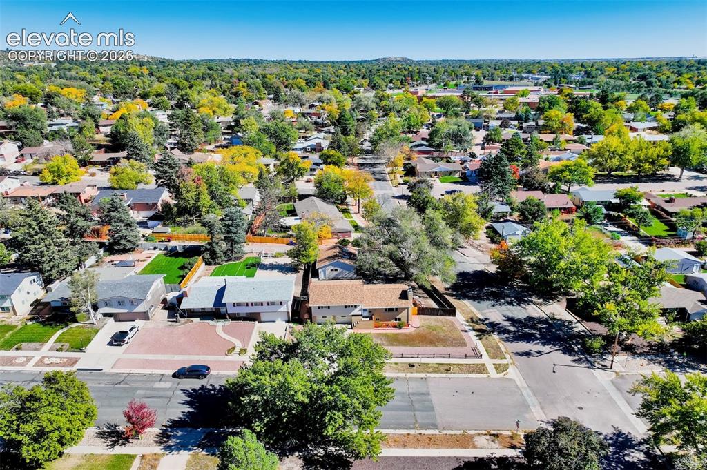 Image 20 of 50: Aerial perspective featuring a residential lot with mature trees, a multi-c