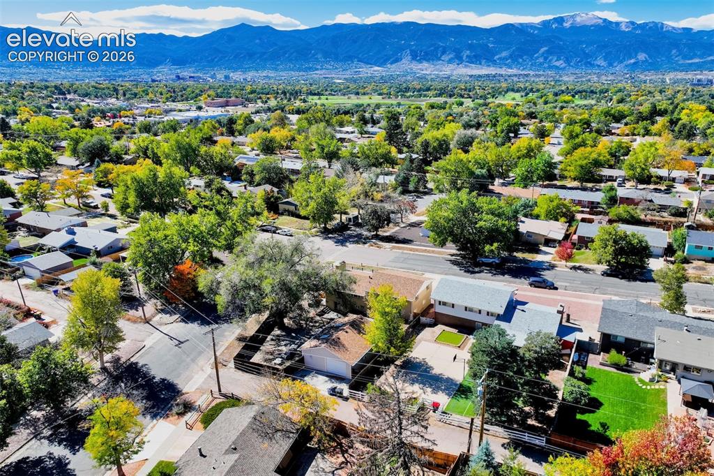 Image 21 of 50: Aerial perspective featuring mountain range backdrop, mature canopy trees, 