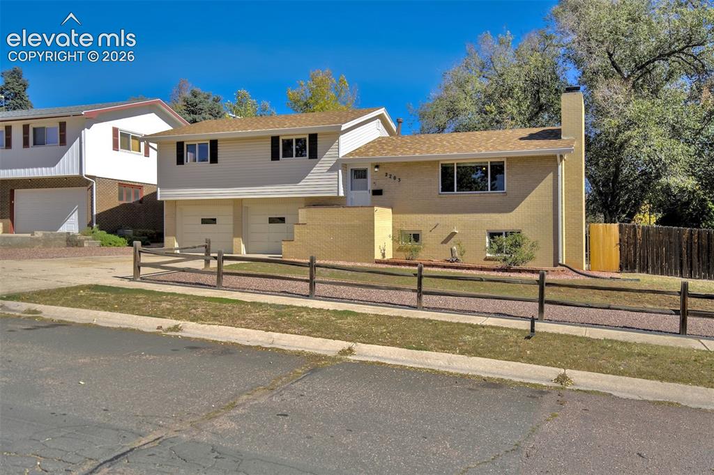 Image 3 of 50: Split-level exterior featuring tan brick and horizontal siding, an attached