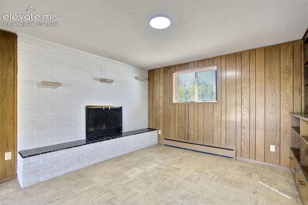 Image 33 of 50: Painted white brick fireplace featuring a black tile hearth, vertical wood-