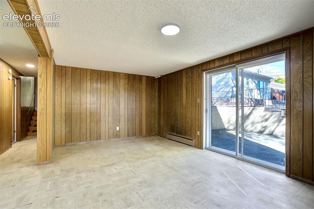 Image 36 of 50: Interior room featuring floor-to-ceiling wood paneling, sliding glass patio