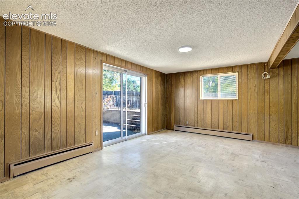 Image 37 of 50: Interior space featuring wood paneling, sliding glass door, single-pane win
