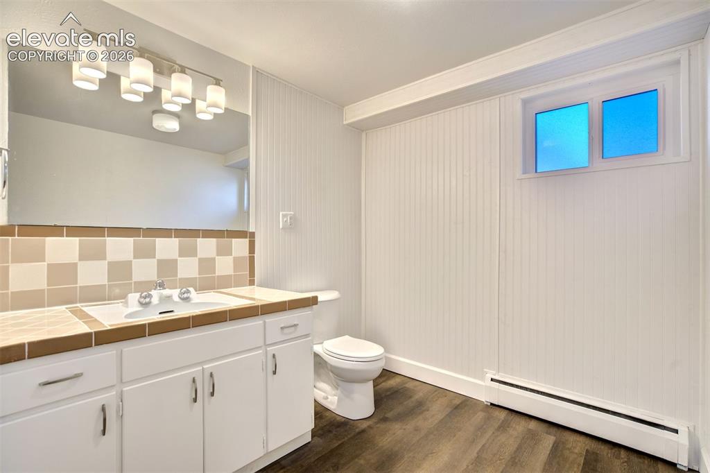 Image 41 of 50: Vanity featuring white cabinetry, a ceramic tiled countertop with integrate