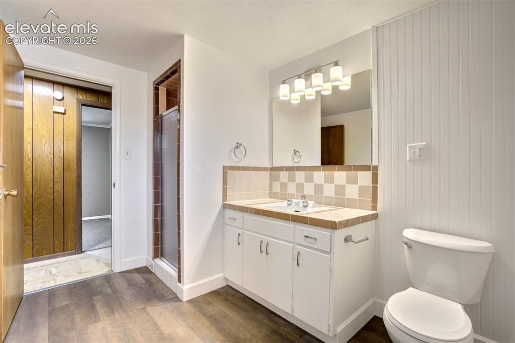 Image 42 of 50: Bathroom featuring a vanity with white cabinetry, tile countertop, beadboar