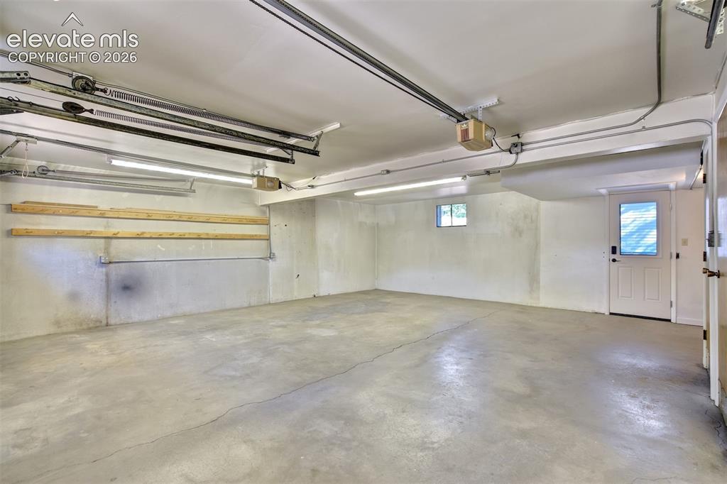 Image 43 of 50: Garage space featuring concrete flooring, overhead lighting, built-in woode