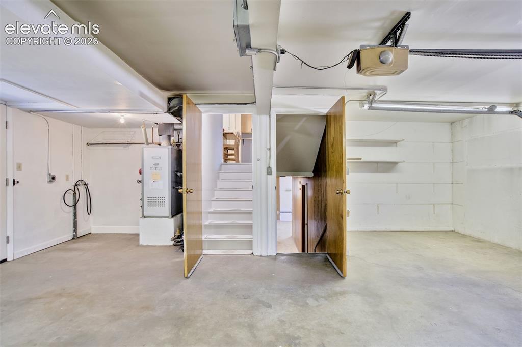 Image 45 of 50: Enclosed garage space featuring painted masonry walls, concrete flooring, b