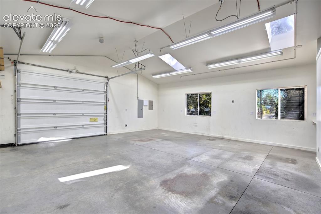 Image 47 of 50: Spacious garage featuring concrete flooring, a sectional overhead door, sky