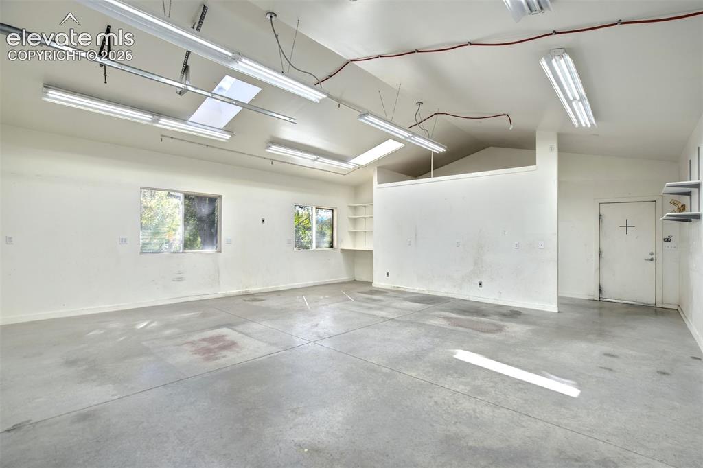 Image 48 of 50: Spacious workshop area featuring high vaulted ceilings, multiple linear flu