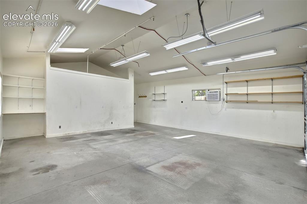 Image 49 of 50: Spacious garage featuring vaulted ceilings, linear fluorescent lighting, bu