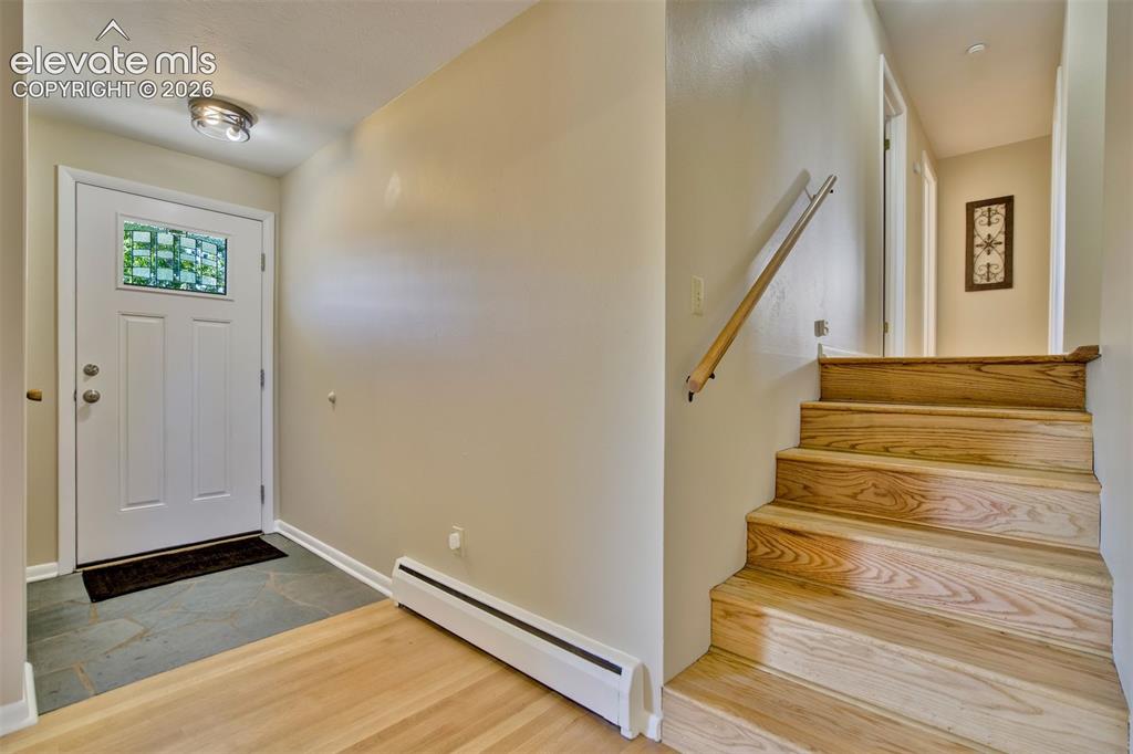 Image 6 of 50: Entryway featuring a white door with a decorative glass insert, slate tile