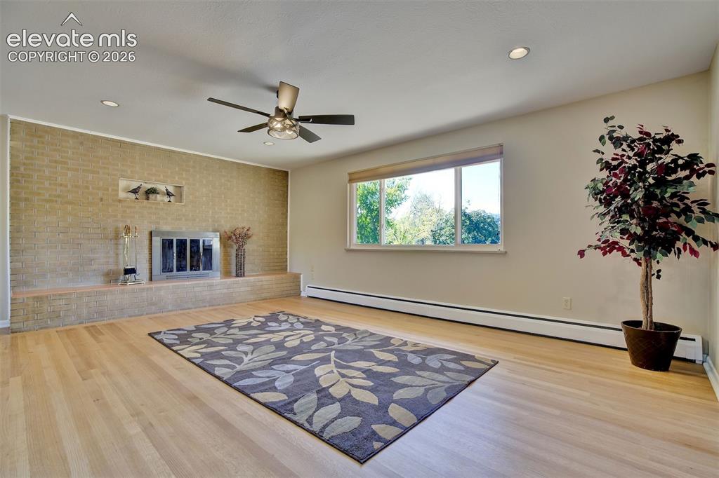 Image 7 of 50: Living area featuring wood-finish flooring, a full-height brick fireplace w