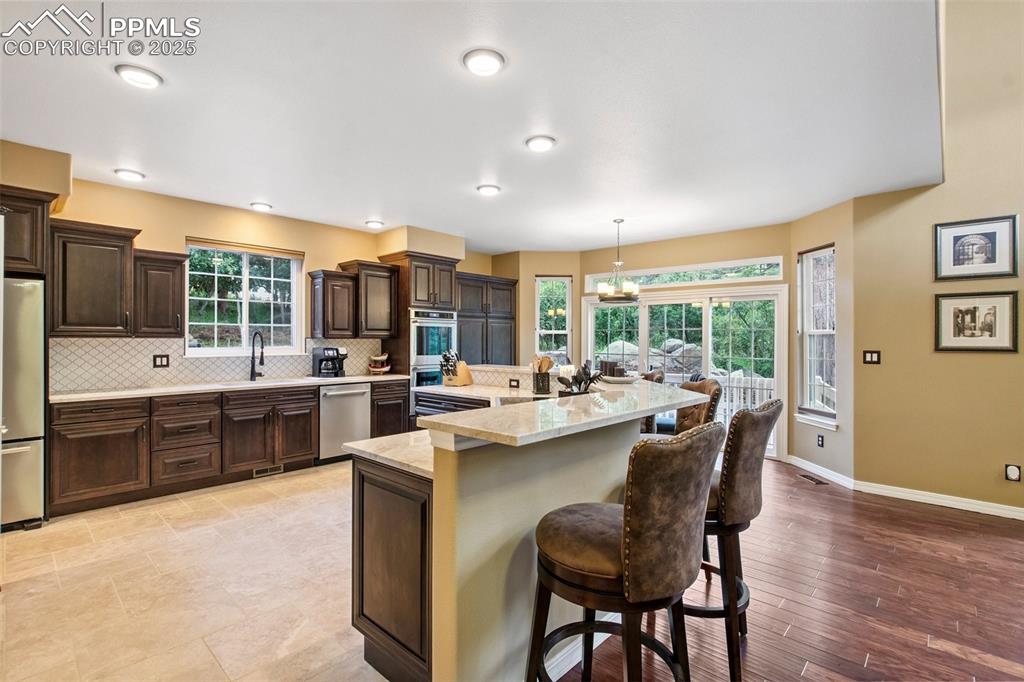 Image 12 of 44: Kitchen with appliances with stainless steel finishes, backsplash, a breakf