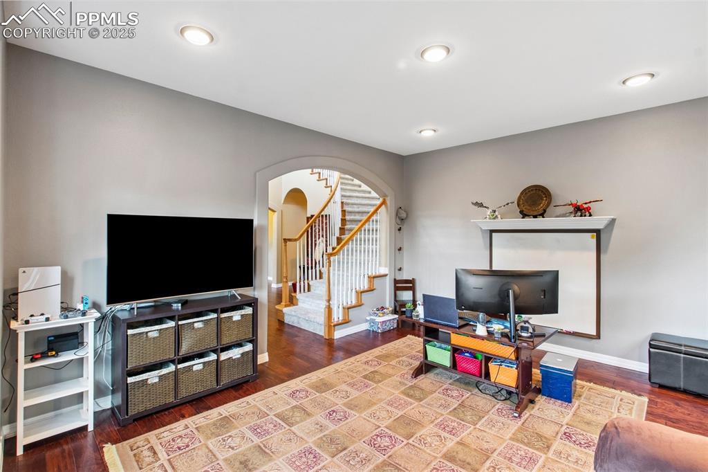 Image 16 of 44: Living area with stairway, arched walkways, and wood finished floors