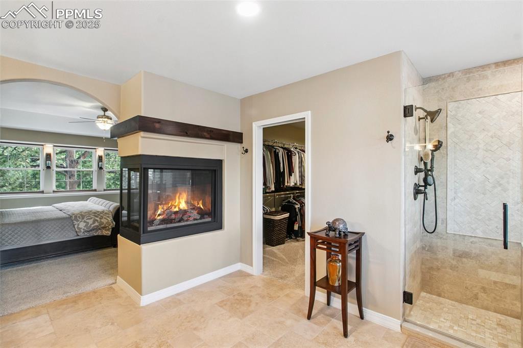 Image 23 of 44: Bedroom with a multi sided fireplace, a walk in closet, arched walkways, an