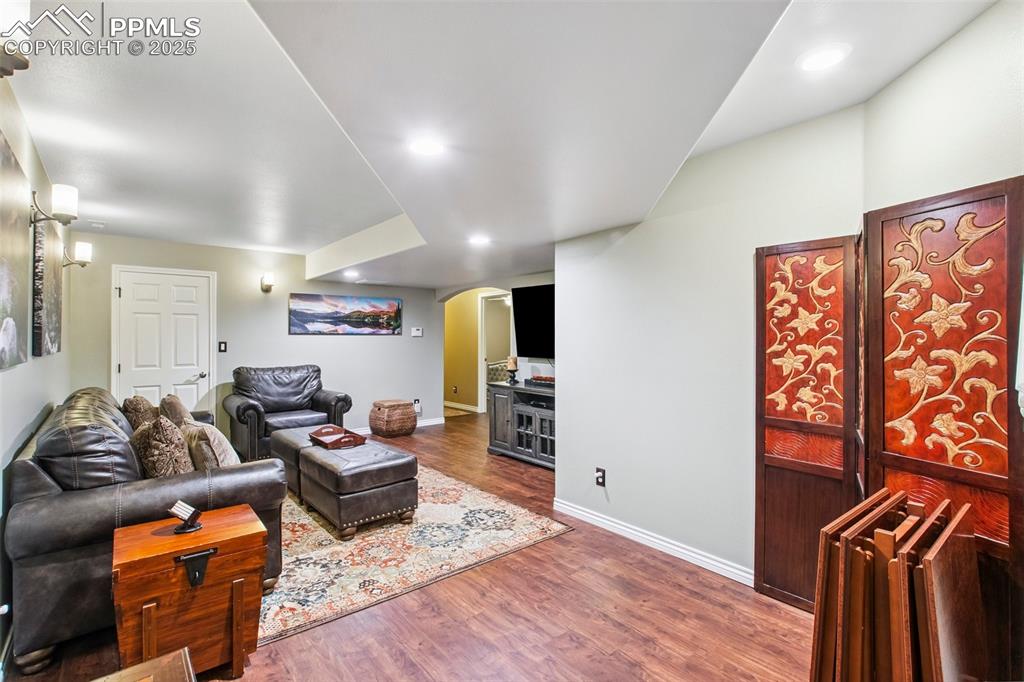 Image 32 of 44: Living area with arched walkways, wood finished floors, and recessed lighti