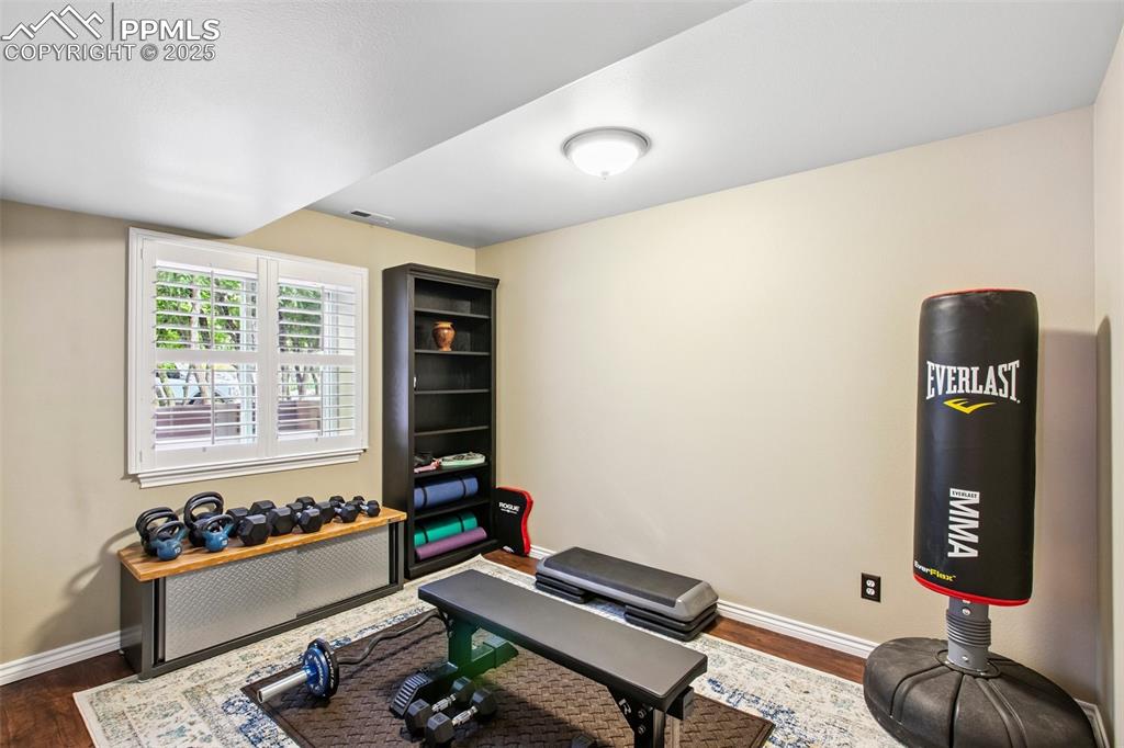 Image 36 of 44: Exercise room with radiator heating unit and dark wood-style flooring