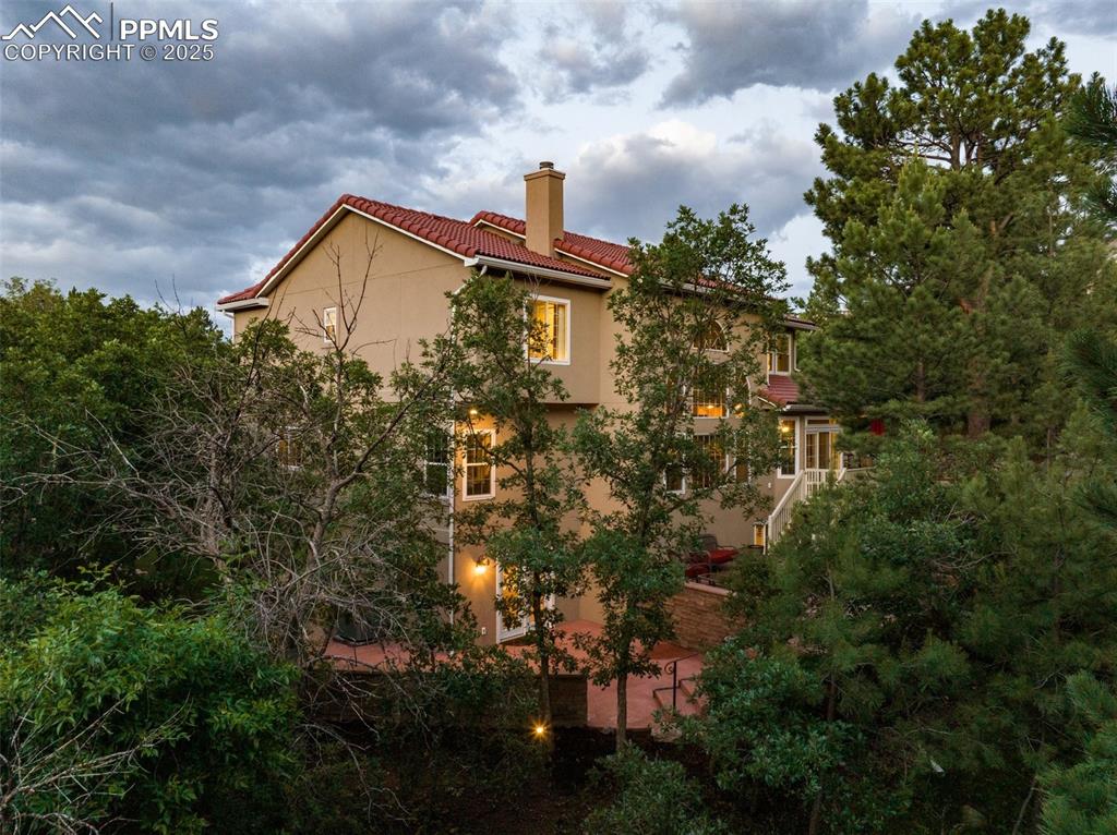 Image 41 of 44: View of side of home featuring a chimney, a tiled roof, and stucco siding