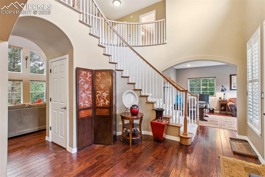 Image 7 of 44: Staircase featuring arched walkways, a high ceiling, and hardwood / wood-st
