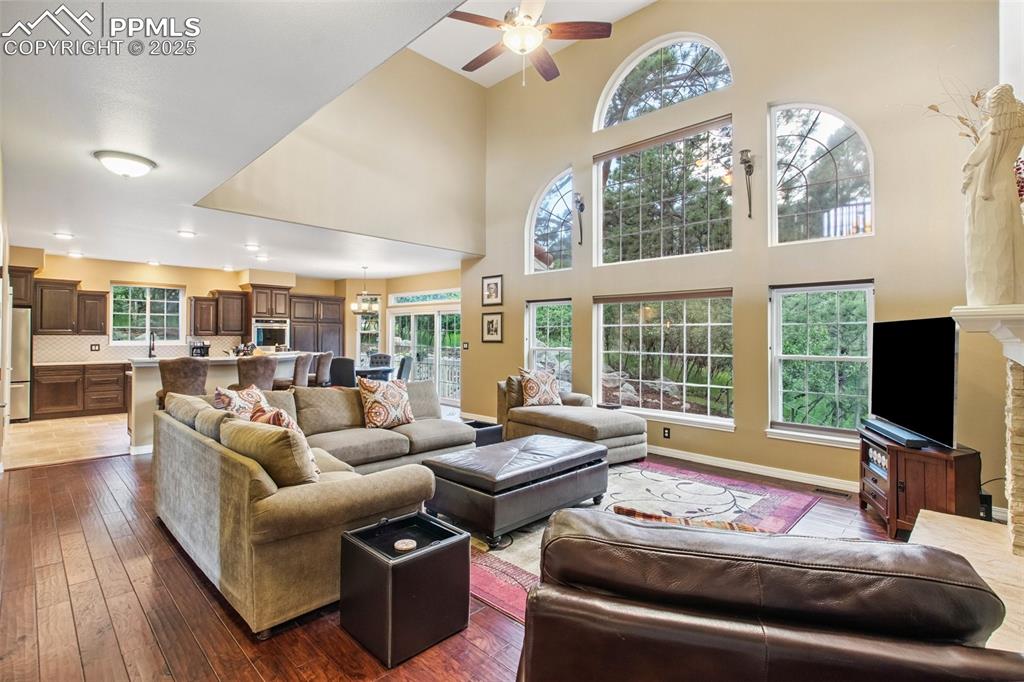 Image 8 of 44: Living room featuring ceiling fan, dark wood-style flooring, and a towering