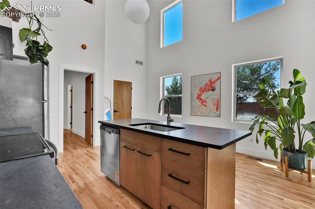 Image 11 of 49: Kitchen featuring brown cabinets, dark countertops, a center island with si