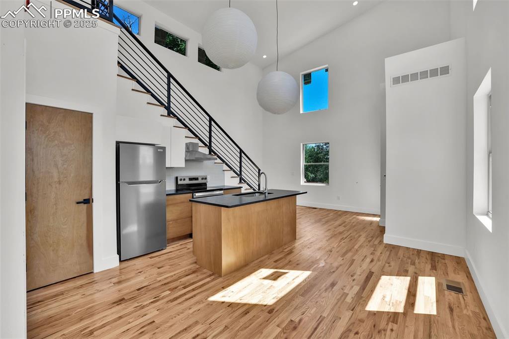 Image 26 of 49: Kitchen with stainless steel appliances, a high ceiling, a kitchen island w
