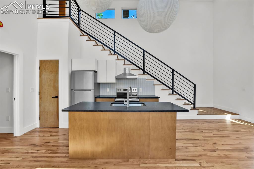 Image 27 of 49: Kitchen with dark countertops, light wood-style flooring, stainless steel a