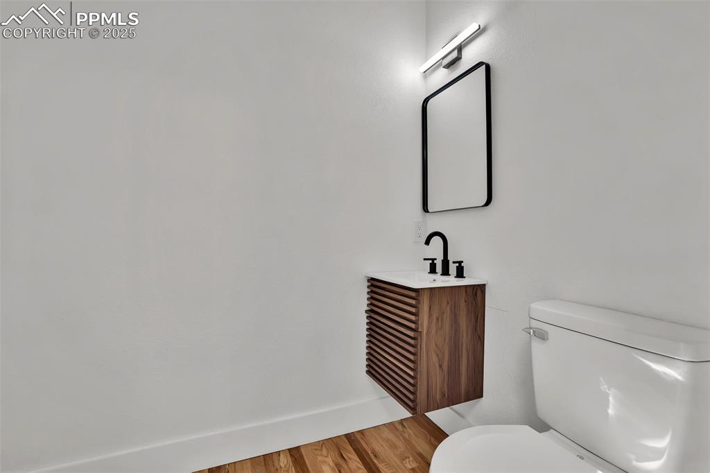 Image 32 of 49: Half bath with light wood-type flooring and vanity