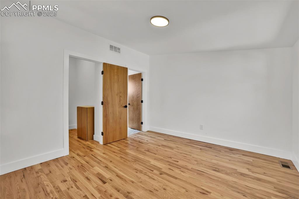 Image 34 of 49: Unfurnished room with wood finished floors and baseboards