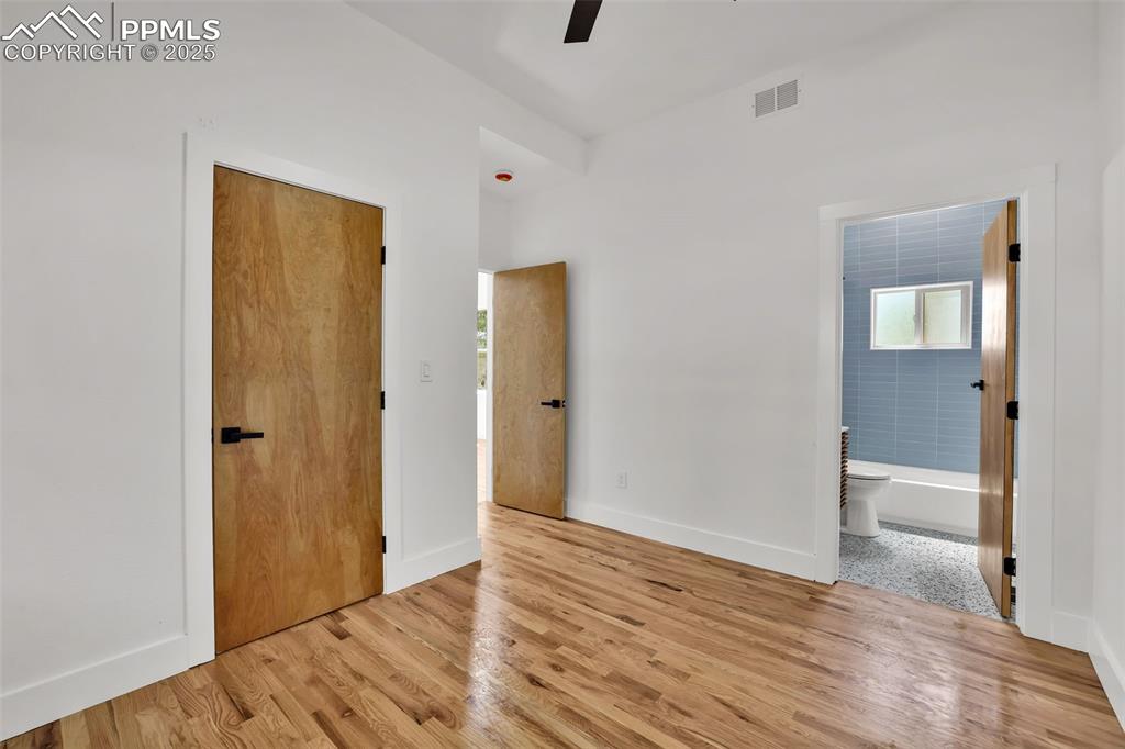 Image 38 of 49: Unfurnished bedroom with wood finished floors, ceiling fan, and connected b