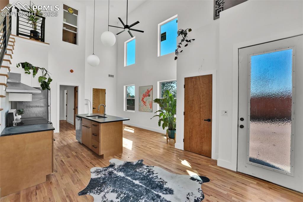 Image 5 of 49: Kitchen with a ceiling fan, a towering ceiling, light wood finished floors,