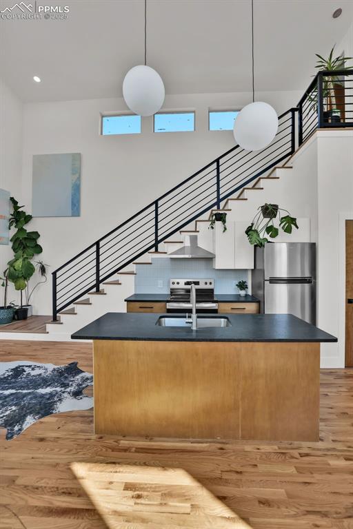 Image 8 of 49: Kitchen with dark countertops, a center island with sink, pendant lighting,