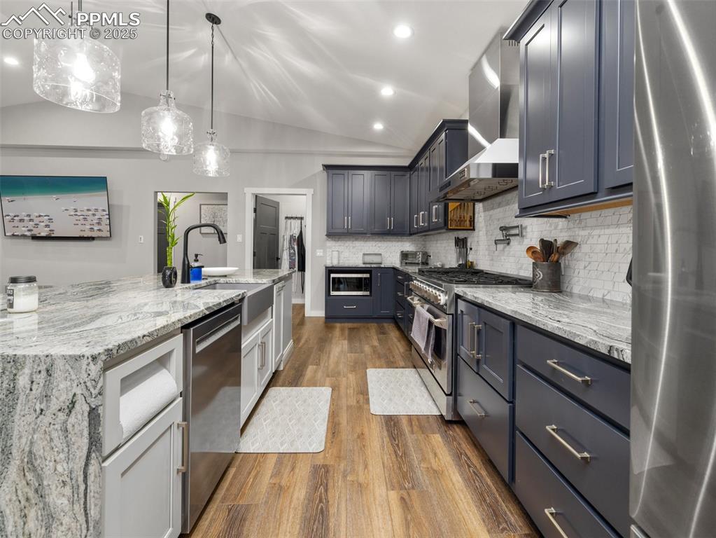 Image 10 of 48: Kitchen featuring appliances with stainless steel finishes, wall chimney ra