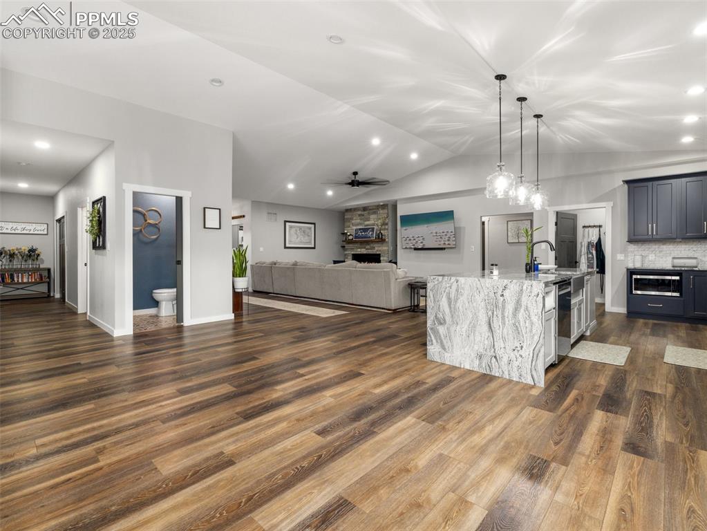 Image 11 of 48: Living room featuring dark wood-style flooring, a ceiling fan, lofted ceili
