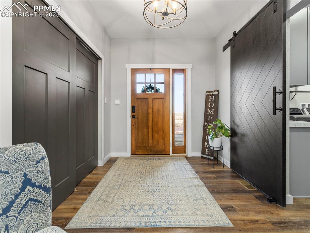 Image 2 of 48: Entrance foyer featuring dark wood-type flooring, a chandelier, and a barn 