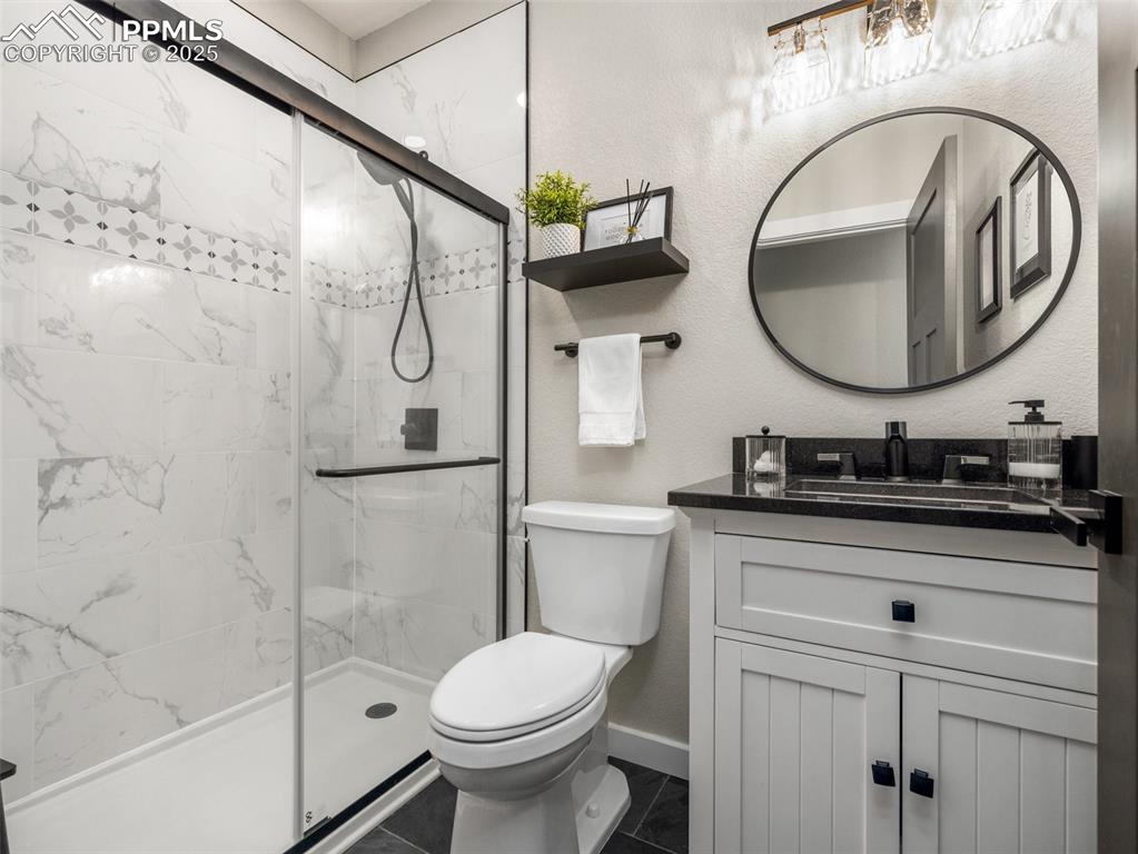 Image 26 of 48: Full bath with vanity, a stall shower, tile patterned floors, and a texture