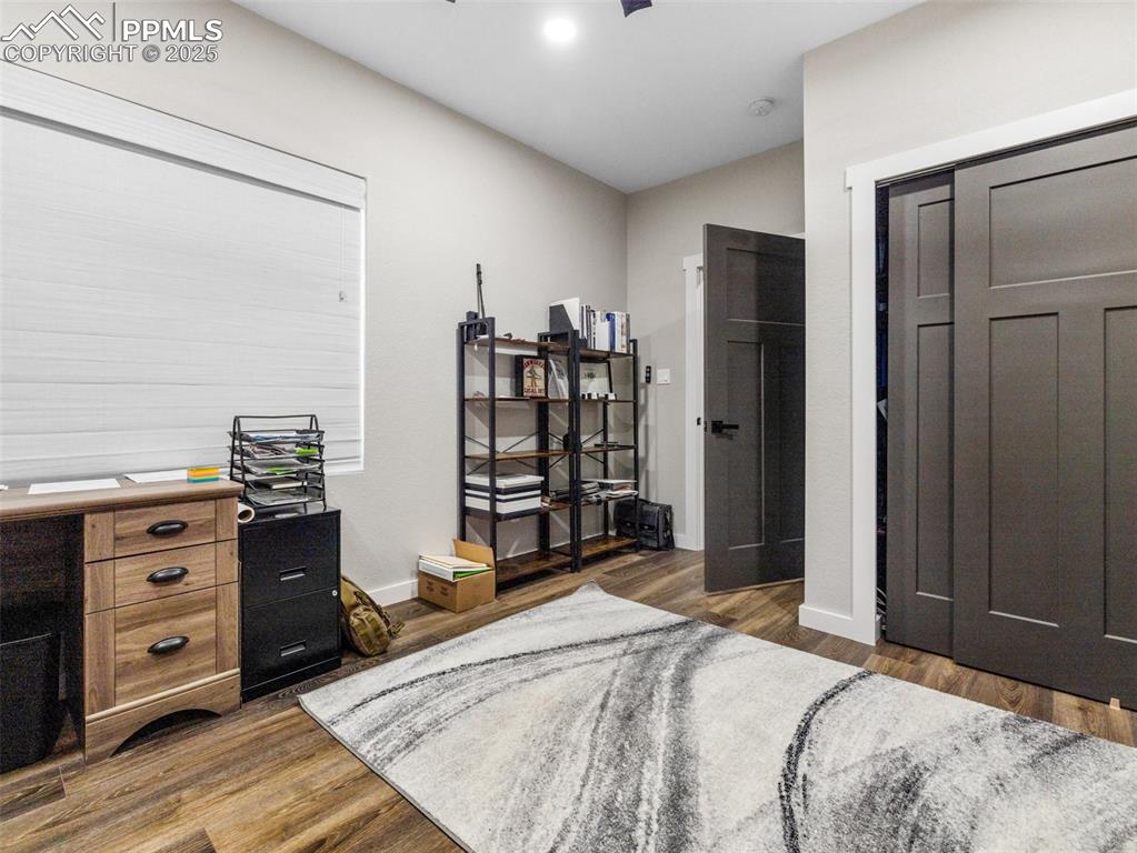 Image 28 of 48: Bedroom with dark wood-style flooring and baseboards