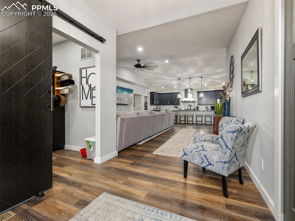 Image 3 of 48: Living room featuring a barn door, a ceiling fan, dark wood finished floors