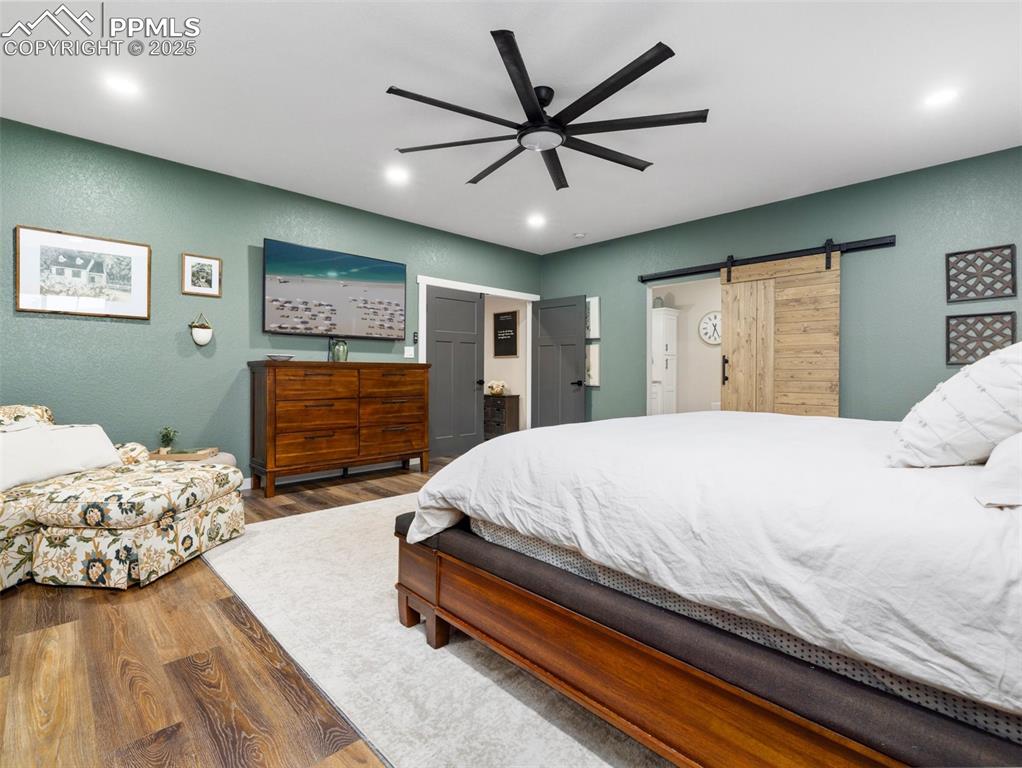 Image 37 of 48: Bedroom featuring wood finished floors, a barn door, recessed lighting, a t