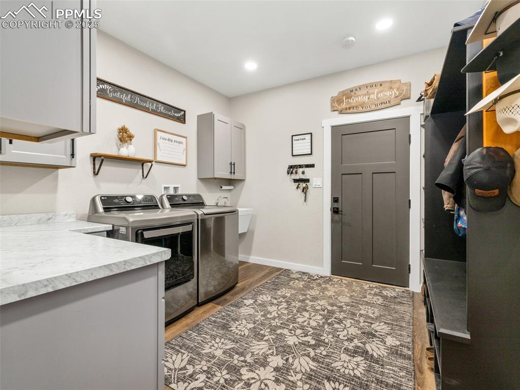 Image 4 of 48: Laundry room with cabinet space, washer and dryer, wood finished floors, an