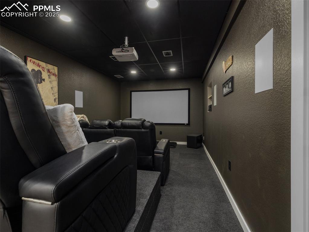 Image 45 of 48: Cinema with a textured wall, dark carpet, a paneled ceiling, and recessed l