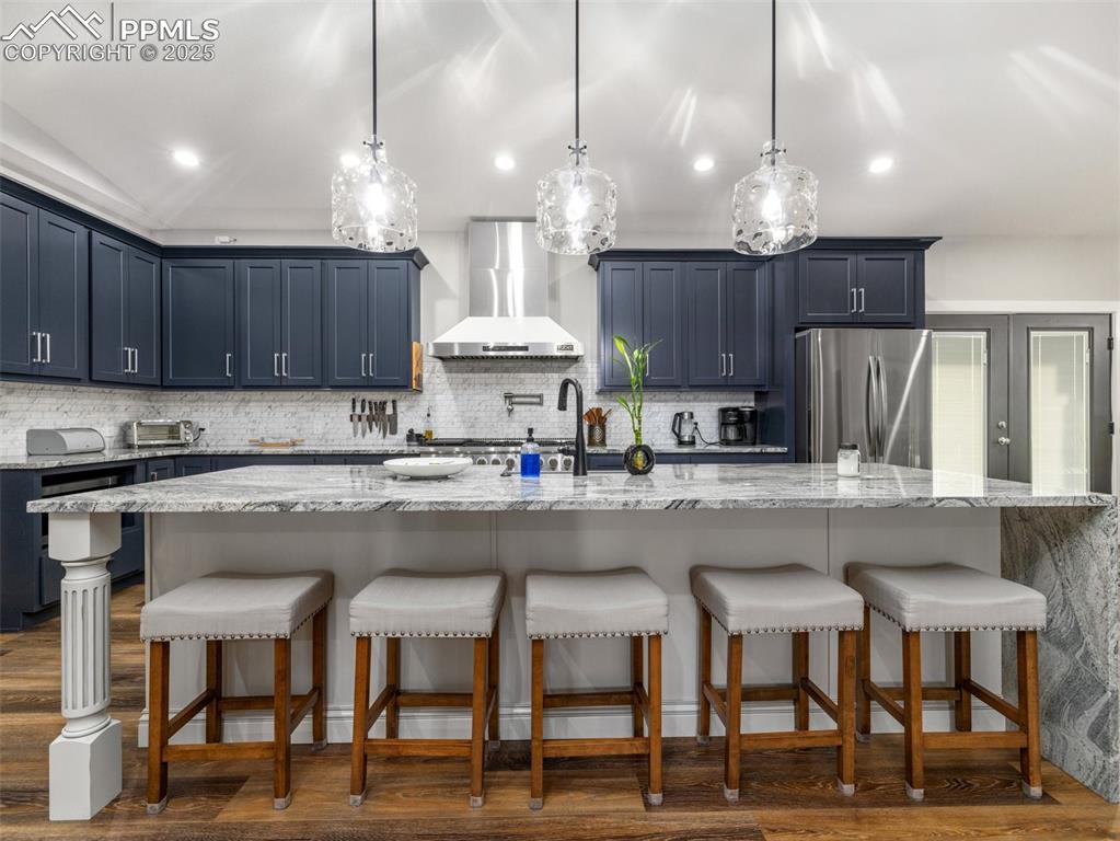 Image 9 of 48: Kitchen featuring wall chimney exhaust hood, freestanding refrigerator, bac