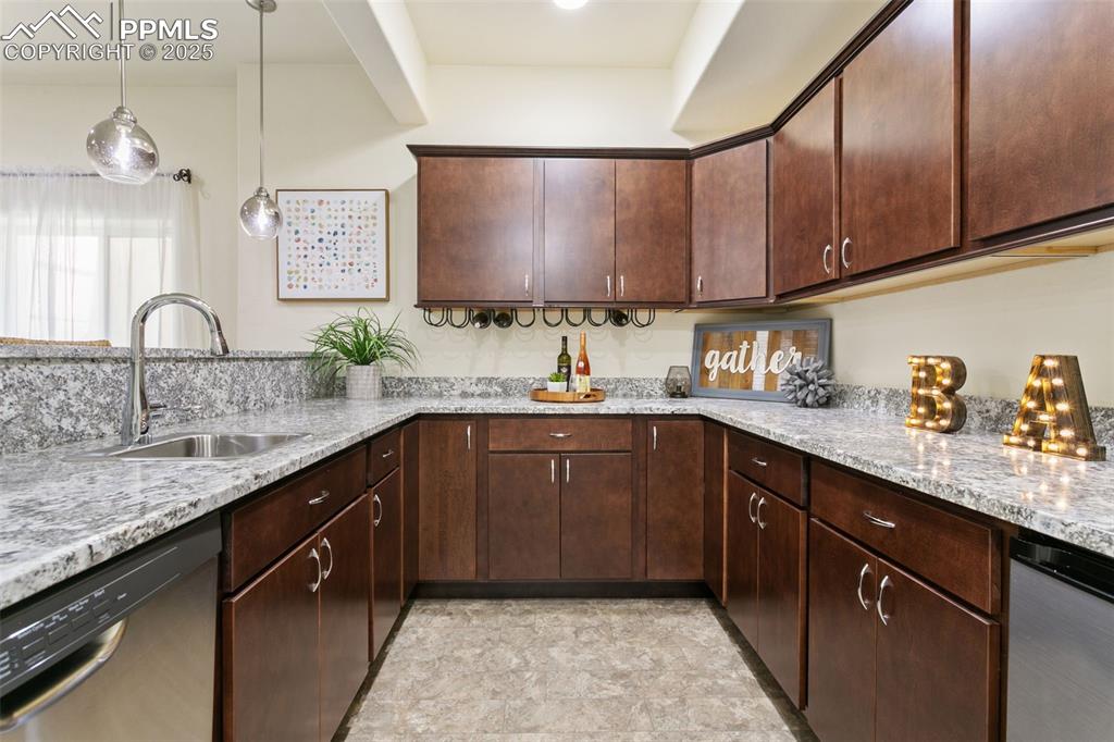 Image 11 of 49: Nice wet bar with rich cabinetry, stainless steel dishwasher, pendant light