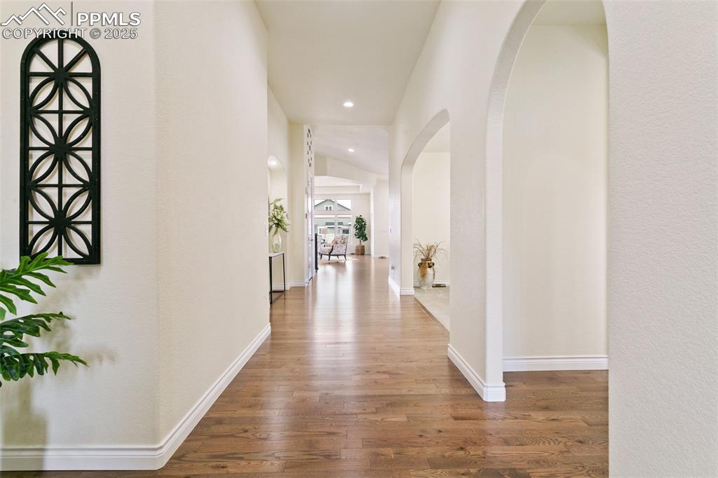 Image 15 of 49: Hallway featuring wood finished floors, recessed lighting, and arched walkw
