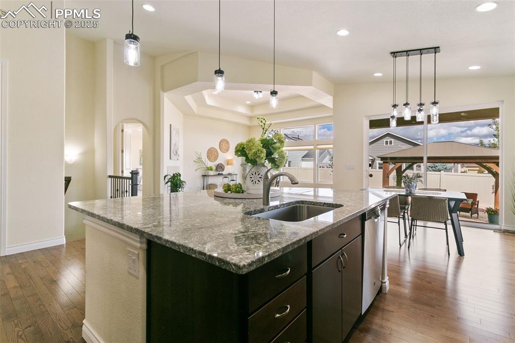 Image 20 of 49: Kitchen featuring pendant lighting, wood finished floors, stone counters,