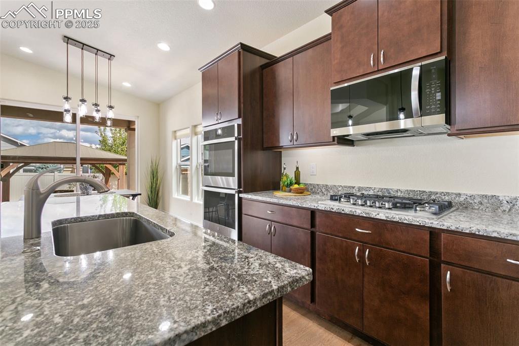 Image 22 of 49: Kitchen with pendant lighting, appliances with stainless steel finishes, ri