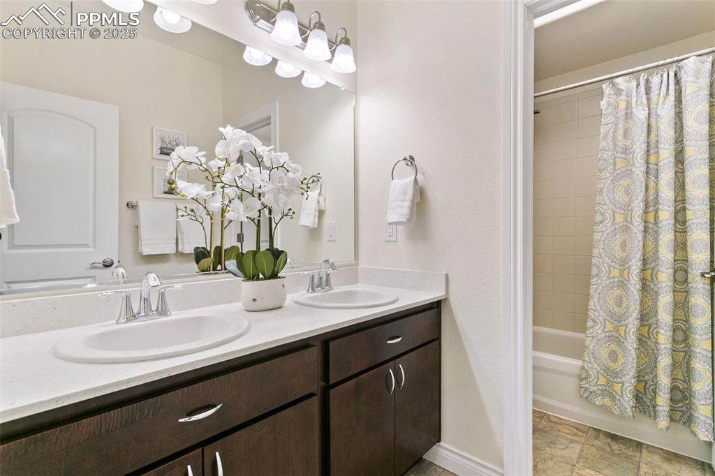 Image 29 of 49: Adjoining Bathroom featuring shower / tub combo with curtain and double van