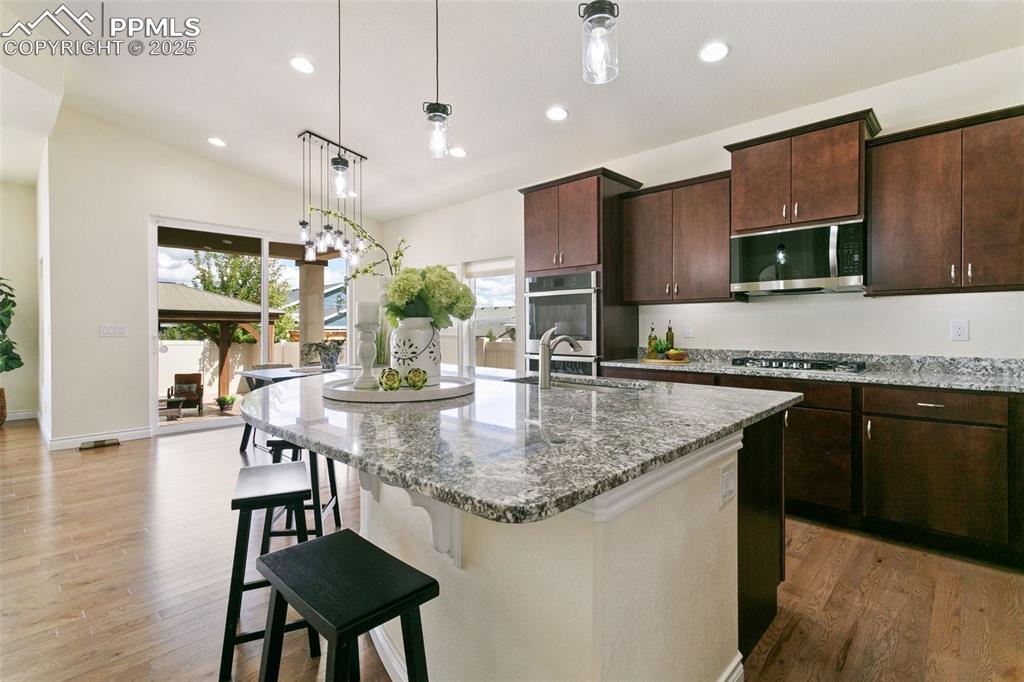 Image 3 of 49: Kitchen featuring rich cabinetry, recessed lighting, light stone counters,