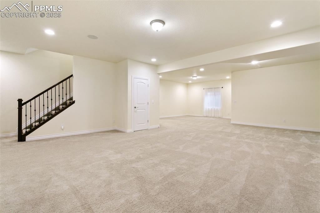 Image 30 of 49: Basement featuring stairway, light carpet, and recessed lighting